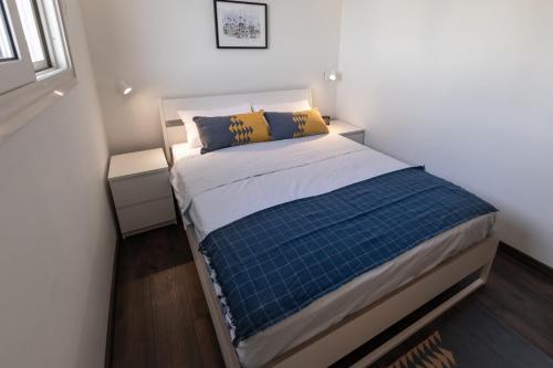 Dormitorio pequeño con cama con almohadas azules y amarillas en Anakob, en Asuán