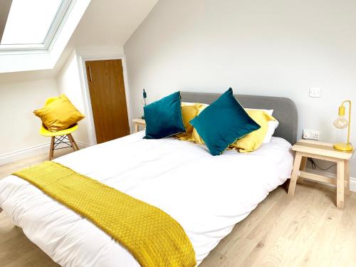 een slaapkamer met een groot bed met blauwe en gele kussens bij The Birches in Cambridge