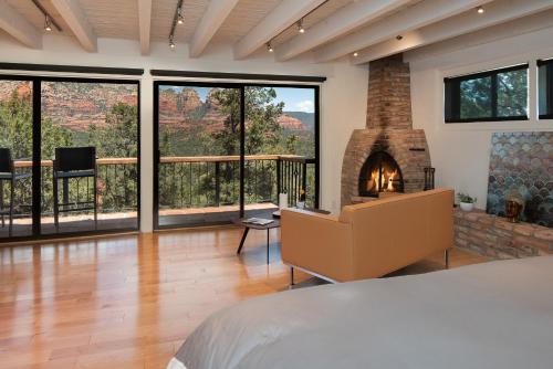 a bedroom with a fireplace and a bed in a room with windows at Private, Modern, Luxury Studio With Unmatched Red Rock Views Private Trail Head - Enjoy on property Sauna, Aromatherapy Steam Room, Hot Tub, Pools and Wellness Services in Sedona
