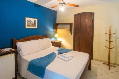 a bedroom with a bed with a blue wall at Pousada Marendaz in Paraty