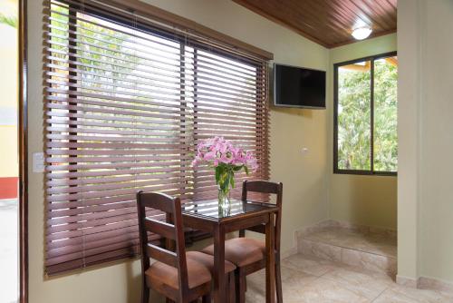 a dining room table with two chairs and a vase of flowers at La Terraza Guest House B&B in Grecia