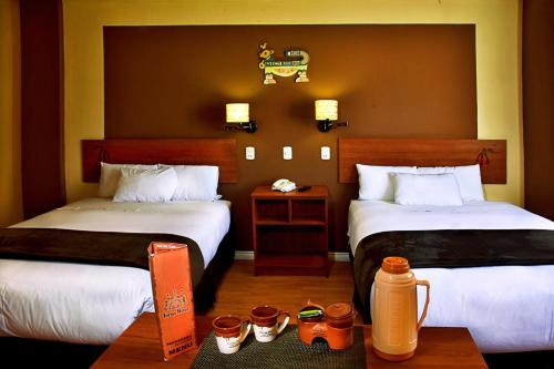 Habitación de hotel con 2 camas y mesa en Intiqa Hotel, en Puno
