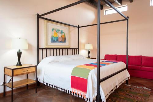 a bedroom with a canopy bed and a red couch at El Macehual in San Miguel de Allende