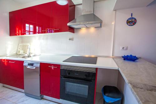 a kitchen with red cabinets and a stove at Apartamento Verena in Puerto del Carmen