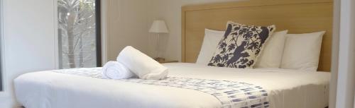 a bedroom with a large white bed with a towel on it at Barwon Heads Resort in Barwon Heads