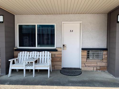 two white benches sitting on the front of a house at City Centre Motel older building in Hope