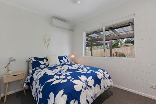 Schlafzimmer mit einem blauen und weißen Bett und einem Fenster in der Unterkunft Whitsunday Palms by HamoRent in Airlie Beach
