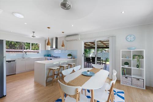 a kitchen and dining room with a table and chairs at Whitsunday Palms by HamoRent in Airlie Beach