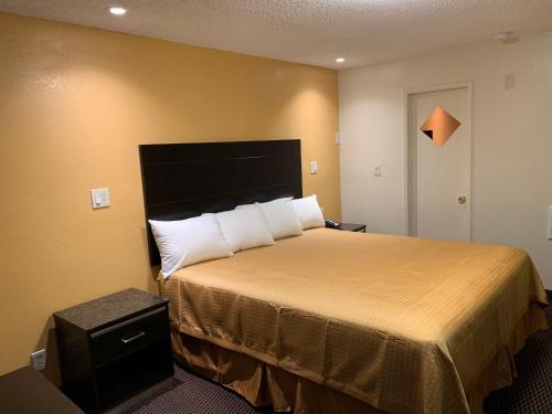una camera d'albergo con letto e cuscini bianchi di Seaview Inn Grover Beach a Grover Beach