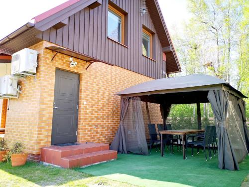 a house with a tent and a table with chairs at Apartamentai Karklėje in Karklė