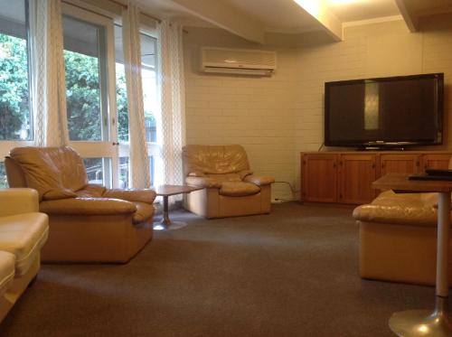 a living room with two chairs and a flat screen tv at Cobram Colonial Motor Inn in Cobram