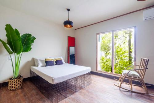 a bedroom with a bed and a window and a chair at The Flying Fish Hostel Cebu in Cebu City