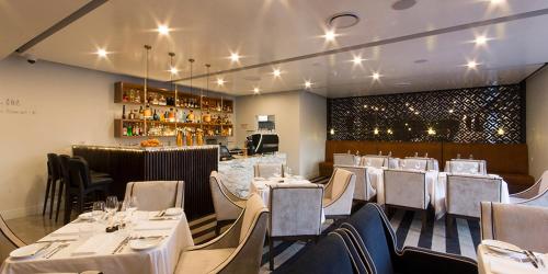 a restaurant with white tables and chairs and a bar at Ellen Hotel in Port Pirie
