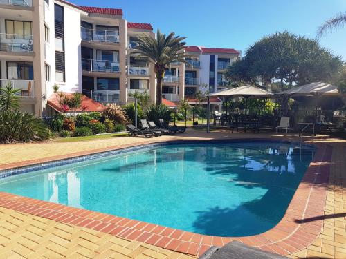 
a large swimming pool in front of a house at Casablanca Beachfront Apartments in Caloundra
