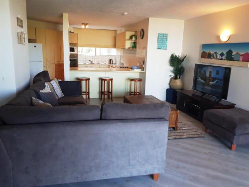 a living room with a couch and a tv at Casablanca Beachfront Apartments in Caloundra
