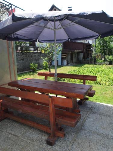 two wooden benches with an umbrella on a patio at Apartments Gale in Delnice