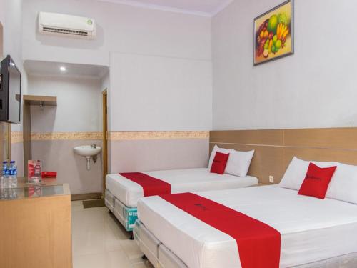 a hotel room with two beds with red accents at RedDoorz near Goa Panggung in Pangandaran