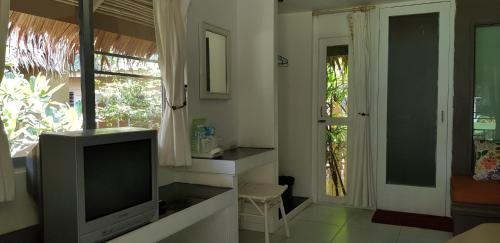 a living room with a tv and a window at Phayam Cottage Resort in Ko Phayam