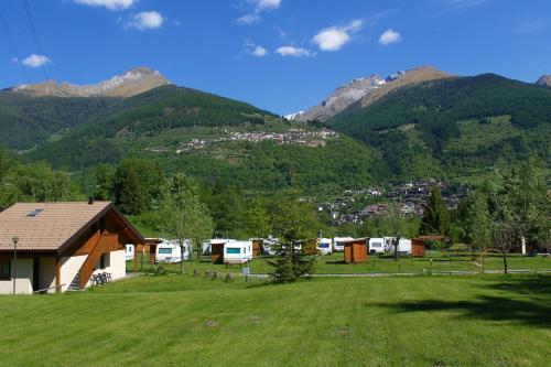 a large field with a house and mountains in the background at Chalet Presanella in Temù