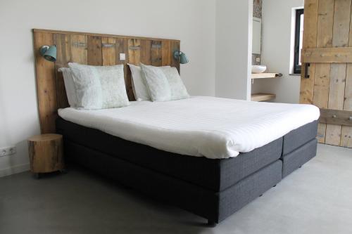 a bedroom with a large bed with a wooden headboard at Zeeuws Kot in Nieuwerkerk