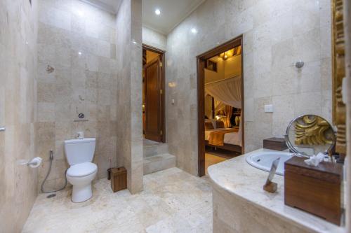 a bathroom with a toilet and a tub and a sink at Bidadari Private Villas & Retreat in Ubud