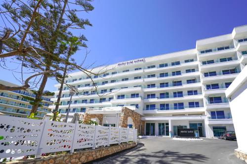 a white building with a fence in front of it at Melini Hotel Suites in Protaras