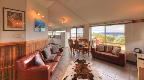 a living room with leather couches and a table with a view at Discover Bruny Island Holiday Accommodation in Alonnah