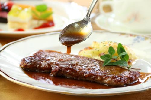 a plate of food with meat and gravy and a spoon at Pension Bloom in Gujo