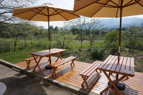 two picnic tables and two umbrellas on a deck at Pension Bloom in Gujo
