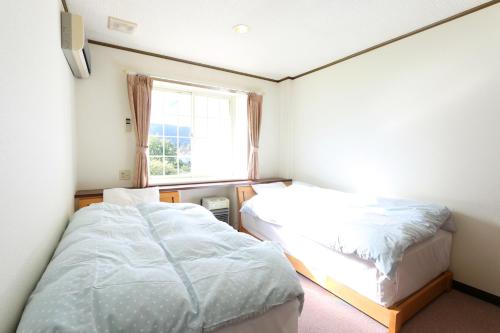 a small room with two beds and a window at Pension Bloom in Gujo