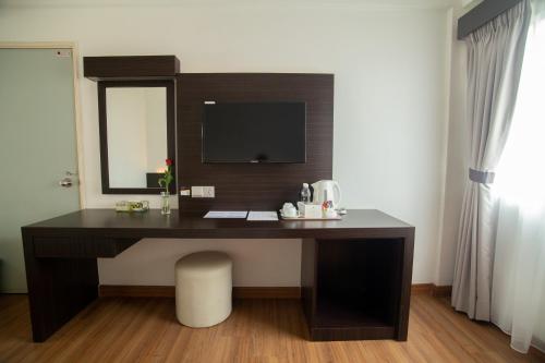 a desk in a room with a television on a wall at Hotel Seri Malaysia Sungai Petani in Sungai Petani