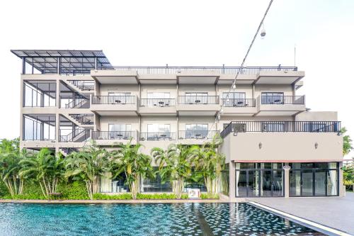 an apartment building with a swimming pool in front of it at Baan Phing Phu Praew Cha-Am Resort บ้านพิงภูแพรว รีสอร์ท ชะอำ in Cha Am