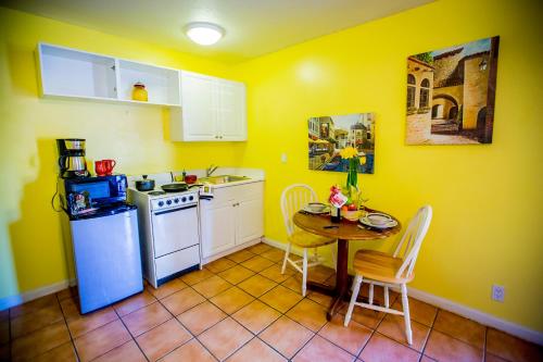 a kitchen with yellow walls and a table and a refrigerator at Leucadia Beach Inn in Encinitas