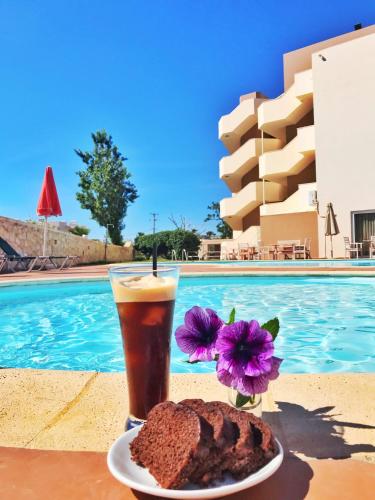 a drink and a plate of food next to a pool at Hermes Hotel in Kissamos