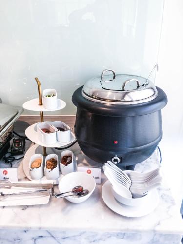a pot and dishes on a counter with a table with food at Fortune Hotel Buriram in Buriram