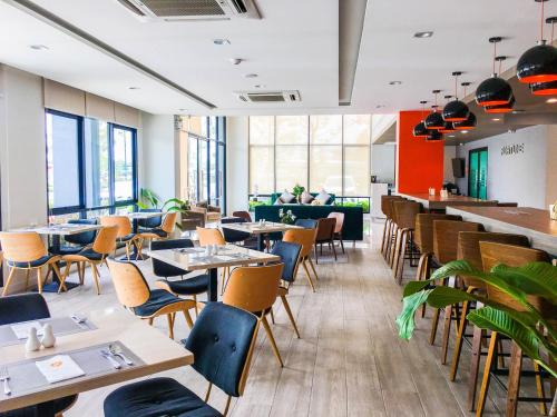 a restaurant with tables and chairs and a couch at Fortune Hotel Buriram in Buriram