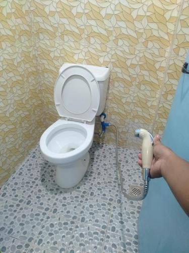a person holding a vacuum cleaner in front of a toilet at Carillo guest house in Coron