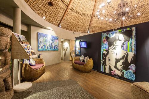 a living room with wicker chairs and a large screen at Blue Karma Dijiwa Seminyak in Seminyak