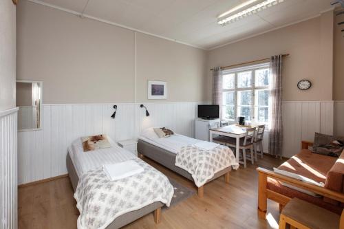 a room with two beds and a table and a desk at Guesthouse Koli Freetime in Ahmovaara