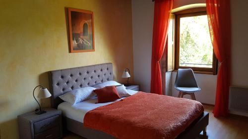 una camera da letto con un letto con una coperta rossa e una finestra di Auberge du Vernay a Charette