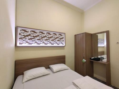 una piccola camera da letto con un letto e uno specchio di De Hanami Homestay a Cirebon