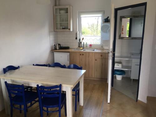 ヤストシェンビャ・グラにあるBiałe domkiのキッチン(テーブル、青い椅子付)