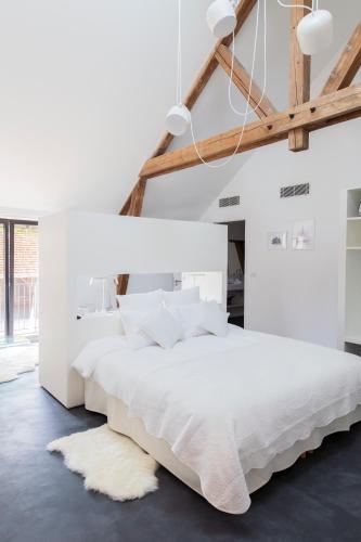 - une chambre blanche avec un grand lit blanc et un tapis dans l'établissement Au Clos du Lac, à Gueux