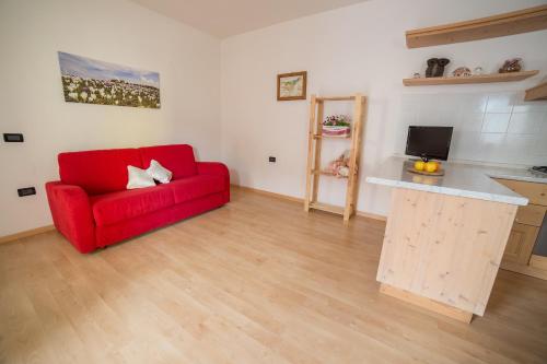 a living room with a red couch and a kitchen at Rothaus in Folgaria