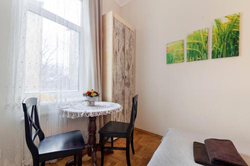 una pequeña mesa y sillas en una habitación con ventana en Apartments WHITE HOUSE, en Leópolis