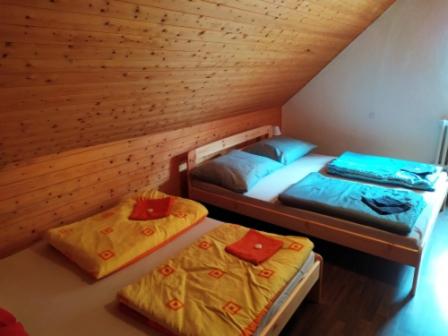 two twin beds in a room with a wooden ceiling at Penzion Zátiší in Komorní Lhotka