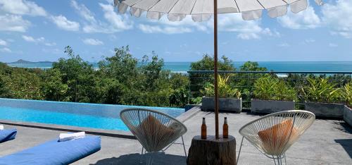 a patio with chairs and an umbrella and a pool at Sky Villa Seren with free car in Laem Set Beach