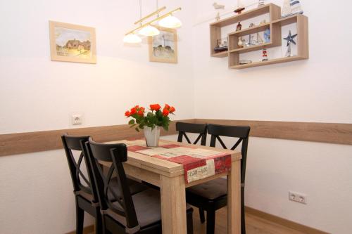 einem Esstisch mit 2 Stühlen und einer Vase aus Blumen in der Unterkunft Ferienwohnung Marina Wendtorf App. 6110 in Wendtorf