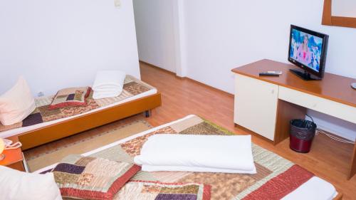 a room with two beds and a desk with a tv at Hotel TEX Club in Botoşani