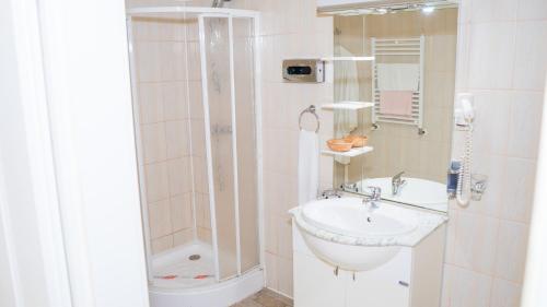 a white bathroom with a sink and a shower at Hotel TEX Club in Botoşani